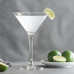 The alcoholic Kamikaze cocktail in a cocktail glass with a wedge lime on a table. Cocktail is made of equal part of vodka, lime juice and triple sec.