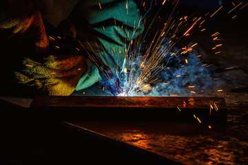 cropped image of manufacture worker welding metal with sparks at factory