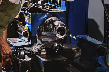 cropped image of male manufacture worker in protective apron using machine tool at factory