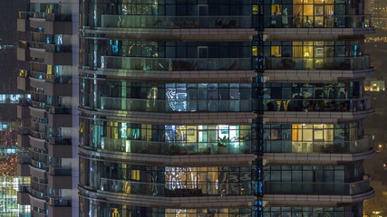 Windows of the multi-storey building of glass and steel lighting inside and moving people within timelapse