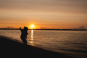 silhouette of a child on the background of the setting sun on the beach