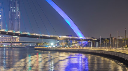 Obraz premium Futuristic Pedestrian Bridge over the Dubai Water Canal Illuminated at Night timelapse, UAE.