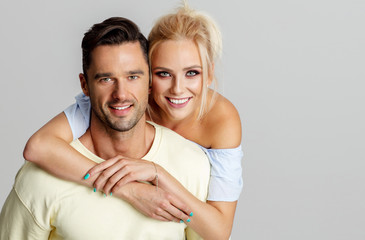 Young adult couple smiling and lookig at camera isolated on gray background