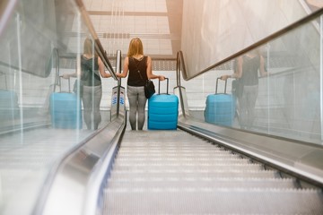 Back view of beauty woman traveling and holding her baggage on escalator
