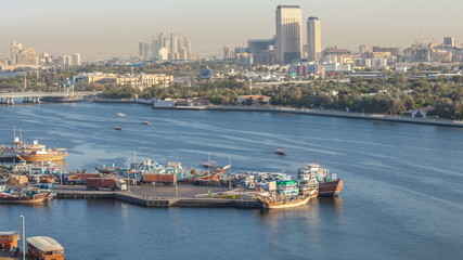 Obraz premium Dubai creek landscape timelapse with boats and ship in port and modern buildings in the background during sunset