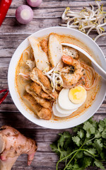 Traditional rice noodles served with spicy broth cooked with coconut milk, topped with egg, prawn and fish cake. Laksa from Singapore.