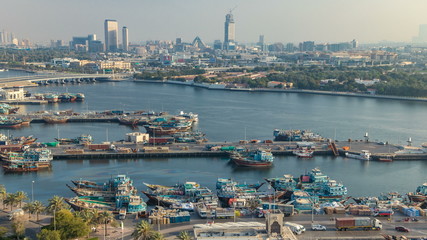Dubai creek landscape timelapse with boats and ship in port and modern buildings in the background during sunset