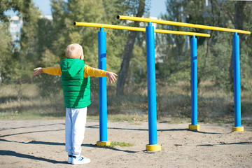 Obraz premium Boy athlete doing pull ups.Active lifestyle. The child performs exercises on uneven bars on the street.