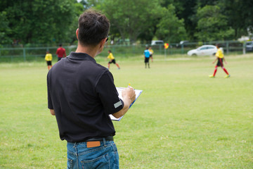 Team Manager Coaching his Crew beside Football or Soccer Field