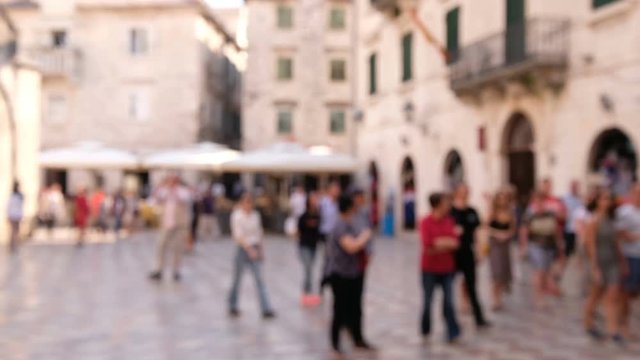 people walking by shops in the daytime in old European city. Blurred background of tourists walking around on street near stores in Rome Italy