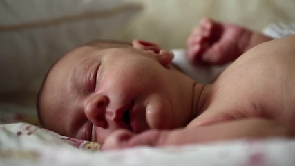 Newborn baby sleeps. Full-term newborn 2 weeks old baby boy lies on the bed and sleeps