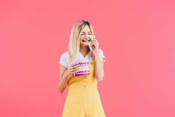 emotional young woman with tissue box crying and wiping tears isolated on pink