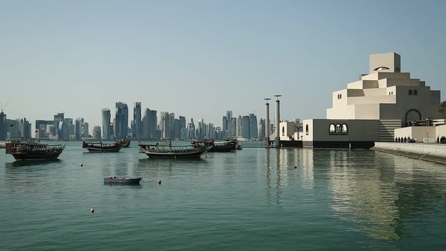 Dhows near museum of islamic art in Doha - capital and most populous city in Qatar, Persian Gulf, Arabian Peninsula, Middle East. Dhow - traditional wooden Qatari boat. Financial centre at background