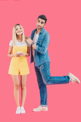 cheerful woman holding smartphone and standing with boyfriend isolated on pink