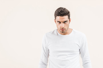 aggressive young man looking at camera isolated on beige