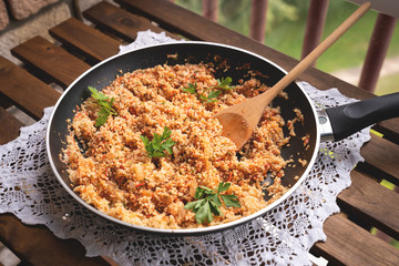 Close-up of a cast-iron frying pan with couscous and cherry tomatoes, selective focus