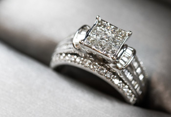 A diamond engagement ring in a box with glint/reflection. Shimmering princess-cut diamonds.