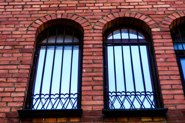 decorative wrought metal fence on the Windows of the Gothic brick house