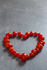 A heart of red tomatoes on a gray background