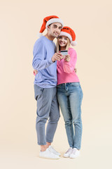 Fototapeta premium happy young couple in santa hats holding credit card and smiling at camera isolated on beige