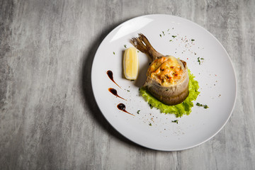 top view on baked trout with stuffing, salad, lemon and sauce