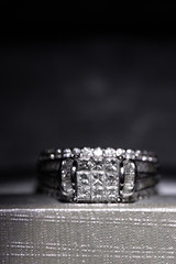 A diamond engagement ring in a box with glint/reflection. Shimmering princess-cut diamonds.