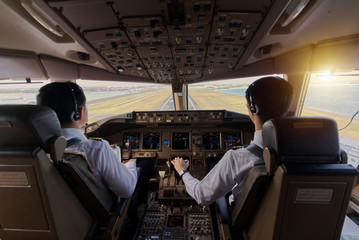 Two airliner pilots are flying the airplane towards the runway. Outside cockpit can see landing...
