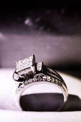 A diamond engagement ring in a box with glint/reflection. Shimmering princess-cut diamonds.