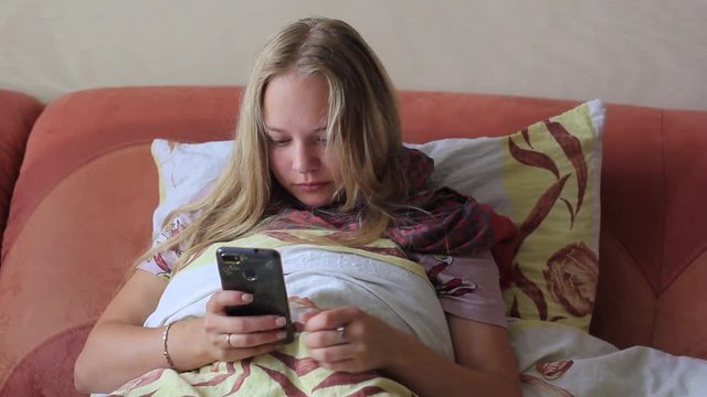 young girl bollet and uses the phone in bed