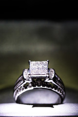 A diamond engagement ring in a box with glint/reflection. Shimmering princess-cut diamonds.
