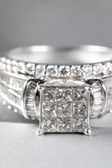 A diamond engagement ring in a box with glint/reflection. Shimmering princess-cut diamonds.