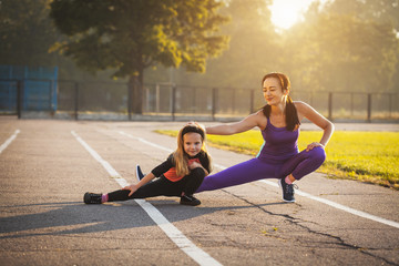 Mom and daughter on the morning sports training do a warm-up