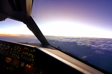 In airplane cockpit view, airplane flying over the cloud during sunset in the evening. Able to see...