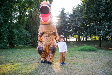Father and son playing at the park, with a dinosaur costume, having fun with the family outdoor © oneinchpunch