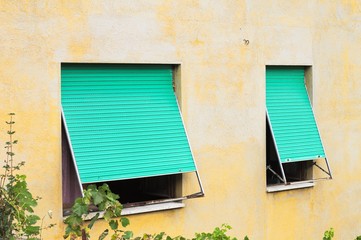 A couple of green windows of a yellow house (Marche, Italy, Europe)