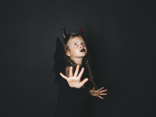 beautiful, blond girl is dressed as halloween devil with red horns and wings