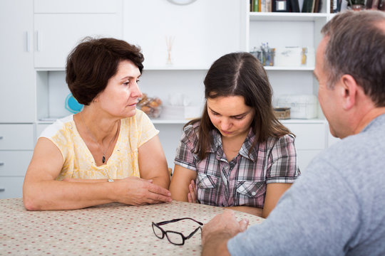 Woman looking sadly while talking with elderly parents