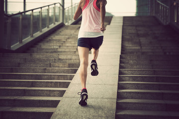 Young woman runner sportswoman running up city stairs jogging and running in urban training workout