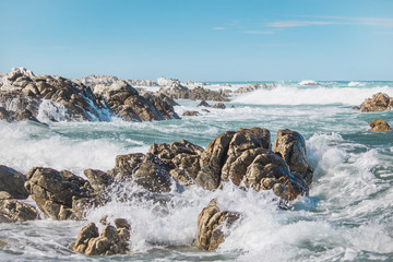 Dramatic crashing waves behind rocks on the shore.