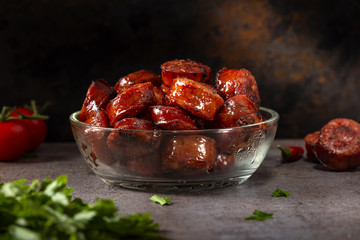 Slices of fried pork sausages in a transparent bowl