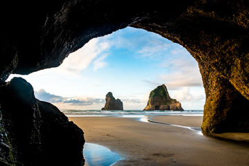 View from the cave of the beautiful Wharariki Beach with famous rocks. Sunset scene golden light and silhouette. Nelson, South Island, New Zealand.