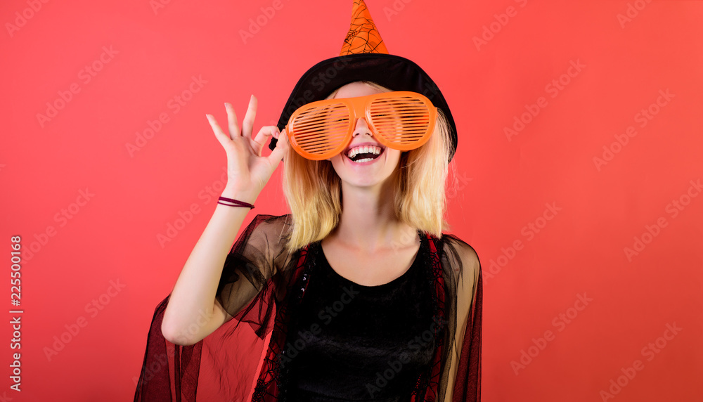 Wall mural Halloween witch in hat show ok sign. Happy girl in halloween costume&big sunglasses. Witch magic. Halloween costume for party. Sexy girl in witch hat celebrate halloween.Attractive woman in witch suit