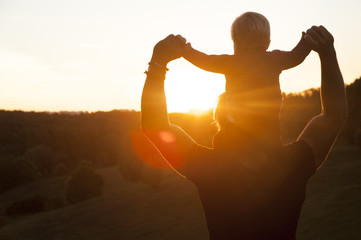 Father and son watching the sunset outdoors in the autumn evening