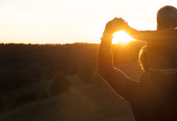 Father and son watching the sunset outdoors in the autumn evening