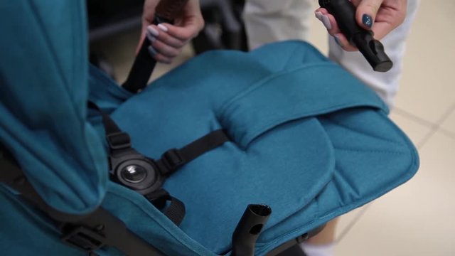 The process of folding a baby stroller in a children's store on the camera.