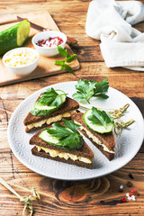 Sandwich with scrambled eggs, cucumbers and parsley on wooden rustic background.