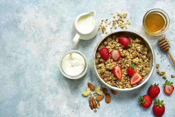 Multicereal homemade organic granola served with fresh strawberry, nuts, honey, milk and yogurt.Top view with copy space.