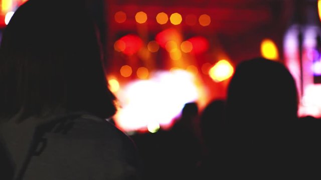 A young blonde is dancing at a rock concert under the light of soffits 4k technology