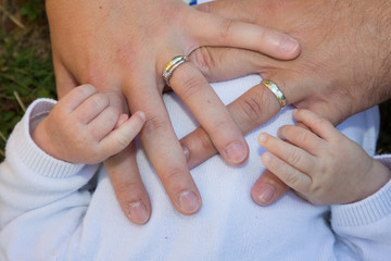 Engagement promise rings couple with baby hand finger on newborn body