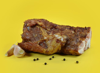 Smoked pork ribs with black pepper and garlic close-up on a yellow background